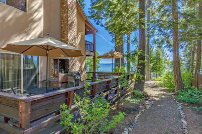 a house with an outdoor patio with an umbrella at Lake Tahoe West Shore Lake Front 5 bedroom Cabin in Homewood