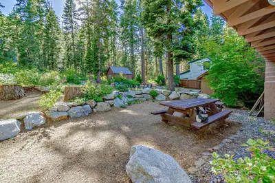 a backyard with a picnic table and a stone wall at Lake Tahoe West Shore Lake Front 5 bedroom Cabin in Homewood