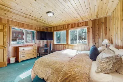 a bedroom with a bed and wooden walls and windows at Tahoe Getaway in Homewood