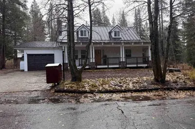 a white house with a garage in the woods at Meyers Tahoe Escape in South Lake Tahoe