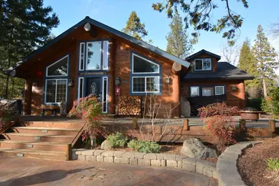 a log cabin with a porch and stairs to a house at Owens Den- Lake AreaFree Night Special in Bass Lake