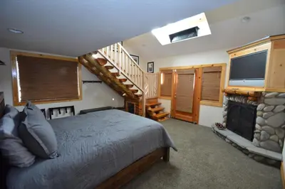 a bedroom with a bed and a tv and a staircase at Owens Den- Lake AreaFree Night Special in Bass Lake