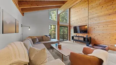 a living room with a couch and a tv and a table at Hot Tub Sauna Forest Views in Tahoe Donner Cedar Summit by Avantstay in Truckee