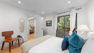 a white bedroom with a bed and a sliding glass door at Hot Tub Sauna Forest Views in Tahoe Donner Cedar Summit by Avantstay in Truckee