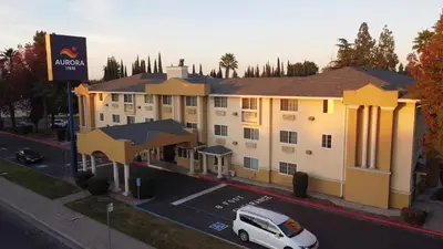 a white van parked in front of a building at Aurora Inn in Modesto