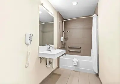 a white bathroom with a sink and a shower at Aurora Inn in Modesto
