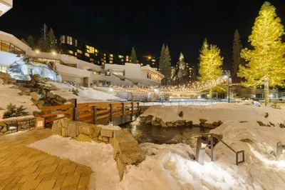 a snow covered resort with a pond and trees at night at Remodeled Second Floor Valley View suite in Olympic Valley