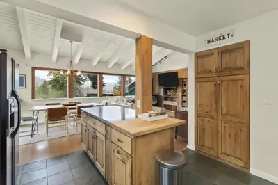 a kitchen with wooden cabinets and a dining room at Panoramic Peaks at Alpine by Tahoe Getaways - Pet Friendly, AC, Hot Tub, Shuttle & Stunning Views in Alpine Meadows