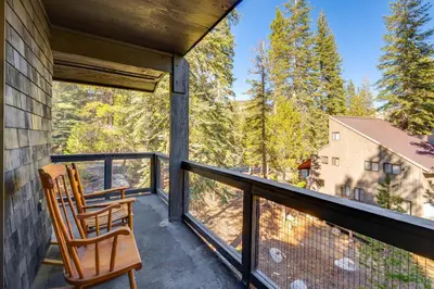 two chairs on a balcony with a view of trees at Ski-InandSki-Out Retreat with Sauna in Bear Valley! in Bear Valley