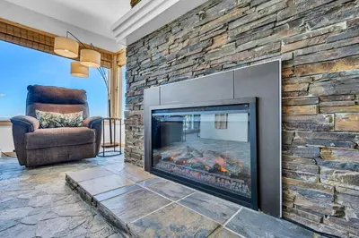 a fireplace in a living room with a stone wall at Wooded Hilltop Stay Shared Hot Tub + Lake Views in Stateline