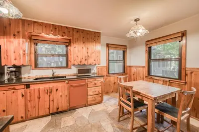 a kitchen with wooden cabinets and a wooden table at Diana's Cabin by Tahoe Getaways - Pet-Friendly 2BR in Kings Beach w Backyard & Walk to Lake! in Tahoe Vista