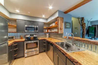 a large kitchen with gray cabinets and stainless steel appliances at Tranquil & Woodsy 2/2 Retreat – Jacuzzi, W/D, BBQ! in Mammoth Lakes
