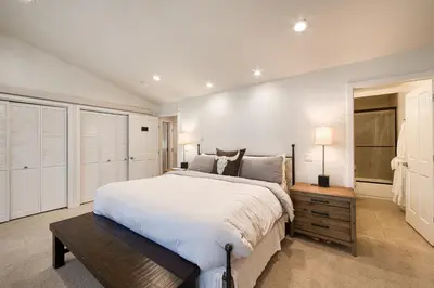 a white bedroom with a large bed and a table at Ridge Court # 13 by Tahoe Getaways - 3BR Palisades at Alpine Condo w Ski Shuttle & Tennis! in Alpine Meadows