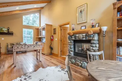 a living room with a stone fireplace and a table at North Shore - Forest Haven in Kings Beach
