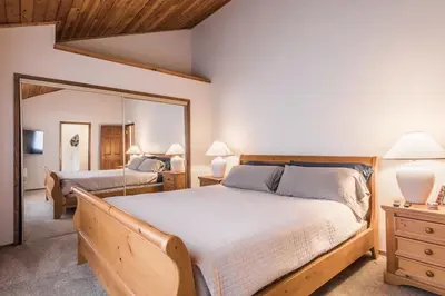 a bedroom with a large bed and a mirror at Spacious 3BD & Loft Villa - Convenient to Slopes in Mammoth Lakes