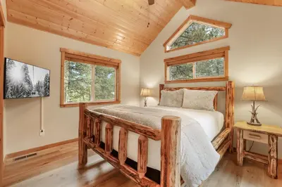 a bedroom with a bed and two windows at Woodlands House home in Truckee