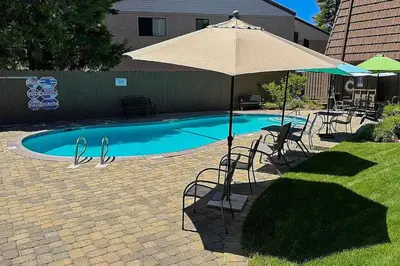 a pool with an umbrella and chairs and a table and chairs sidx sidx at Summit & Shore Chalet in Tahoe Vista