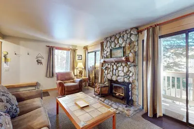 a living room with a stone wall with a fireplace at Hidden Valley 39 E in Mammoth Lakes