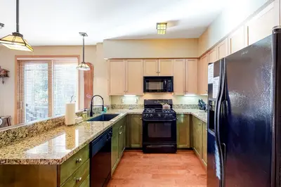 a kitchen with wooden cabinets and a black refrigerator at Mammoth Green 116 in Mammoth Lakes