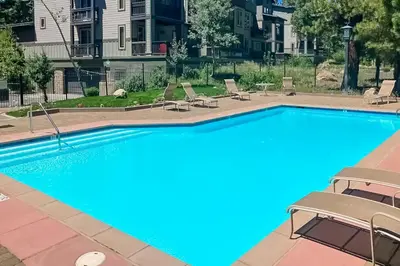 a large swimming pool with lounge chairs around it at Mammoth Green 219 in Mammoth Lakes