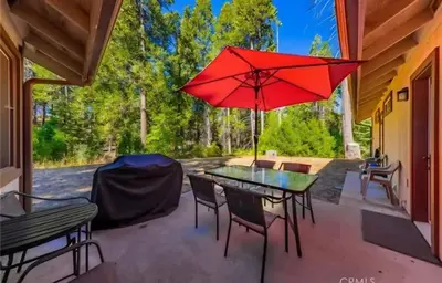 a patio with a table and chairs and a red umbrella at The Lady Bug Family Retreat in Mariposa