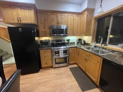 a kitchen with wooden cabinets and a black refrigerator at Mountainside Family Chalet in Yosemite West