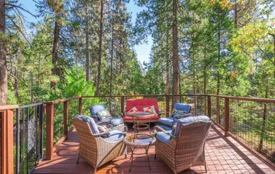 a deck with wicker chairs and a table at Tranquil Treehouse near Fly-In Lake with Deck Dining & BBQ in Arnold