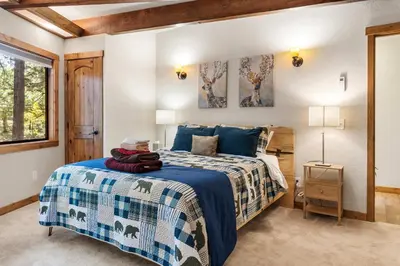 a bedroom with a bed with a blue and white bedspread at Tranquil Treehouse near Fly-In Lake with Deck Dining & BBQ in Arnold