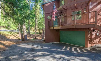 a large house with a garage and a balcony at Tranquil Treehouse near Fly-In Lake with Deck Dining & BBQ in Arnold