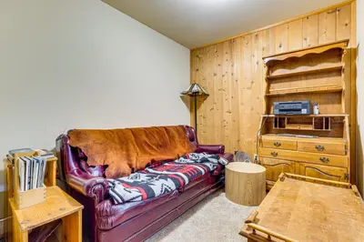 a living room with a leather couch and a wooden wall at 1 Mi to Skiing! Cabin Hideaway on June Lake Loop in June Lake