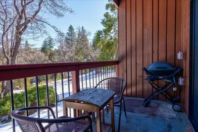 a screened in porch with a grill and two chairs at (A111) Studio Condominiums in Yosemite West