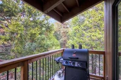 a grill on a balcony with a view of a forest at (B207) Loft Condominiums in Yosemite West