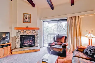 a living room with a fireplace and a chair and a television at (B211) Loft Condominiums in Yosemite West