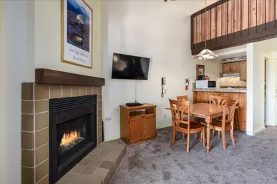 a living room with a fireplace and a table and chairs at (B208) Loft Condominiums in Yosemite West