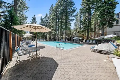 a patio with an umbrella and chairs and a pool at Creekside Chalet Stay for 6 in Kings Beach