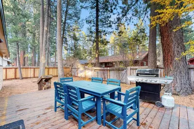 a blue table and chairs on a wooden deck with a grill at Colorado Pines Retreat in South Lake Tahoe