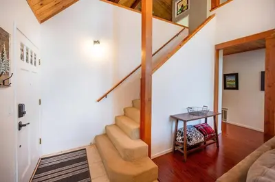 a staircase in a living room with a table at Arnold A Frame Cabin with Hot Tub and Guest Suite in Arnold
