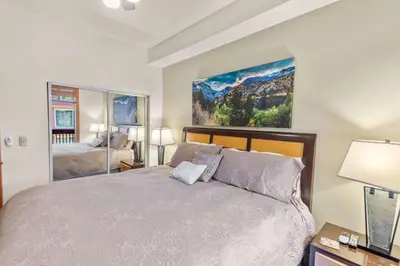 a bedroom with a large bed and a large painting on the wall at The Village #2408 - Village Center Cozy Getaway w Fireplace in Mammoth Lakes