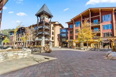 a building with a clock tower in the middle of a street at The Village #2408 - Village Center Cozy Getaway w Fireplace in Mammoth Lakes