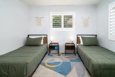 a room with two beds and a table and windows at Serenity Pines 1hr to Yosemite w BBQ and Game Room in Mariposa