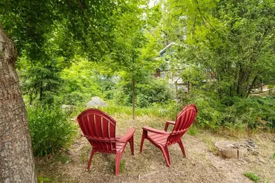 two red chairs and a table in a yard at Serenity Pines 1hr to Yosemite w BBQ and Game Room in Mariposa