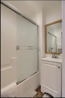 a white bathroom with a shower and a sink at Hillside Bungalow - Walking distance to downtown in Mariposa