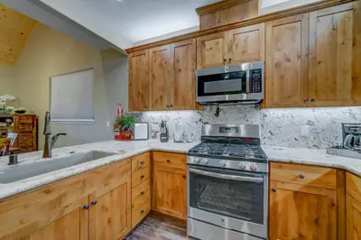a kitchen with wooden cabinets and a stove and a microwave at Butterfly View Retreat - 45 Min to Yosemite in Mariposa