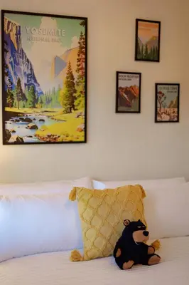 a stuffed bear sitting on a bed with pictures on the wall at Cozy Cabin Near Yosemite & Corlieu Falls in Oakhurst