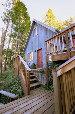 a blue house with a wooden staircase leading up to it at Cozy Cabin Near Yosemite & Corlieu Falls in Oakhurst