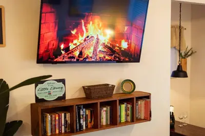 a tv hanging above a book shelf with books at Cozy Cabin Near Yosemite & Corlieu Falls in Oakhurst