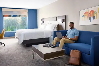 a man sitting on a couch in a hotel room at Holiday Inn Express & Suites Sparks Reno East by IHG in Sparks