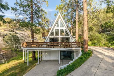 a house with a gambrel roof and a deck at Acorn Falls, Bass Lake, Ca in Bass Lake