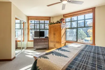 a bedroom with a bed and a tv and windows at Village 1209 in Mammoth Lakes