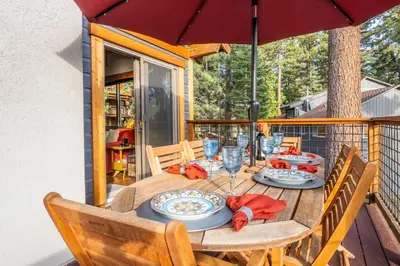 a table on a deck with an umbrella at Boathouse in the Woods by Tahoe Getaways - Minutes to Lake Tahoe & Northstar in Kings Beach